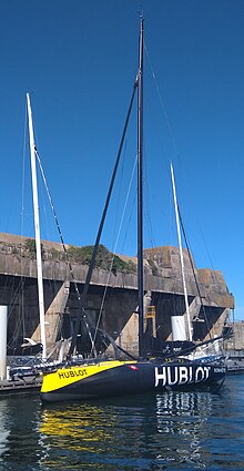 Voilier jaune et noir vu en entier, amarré au ponton, devant l'ancienne basse de sous-marins allemande de Lorient.