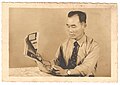 Brazilian issei, (first generation of Japanese immigrant), reading newspaper in Romaji, while the shown title is about Kardec spiritism (a French–Brazilian sect) which is quite similar to Shinto and Buddhist principles.