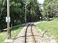 Läutetafel „F“ vor einem kleineren unbeschrankten Bahnübergang