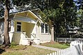 A small yellow house with a white picket fence.