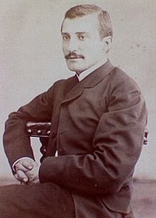 Portrait photographique d'un homme assis sur une chaise.