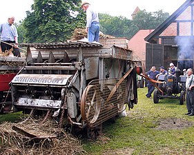 Batteuse entraînée par un semi-diesel Lanz Bulldog . La batteuse est équipée d'une presse basse densité incorporée (au premier plan). Allemagne, machines des années 1950.