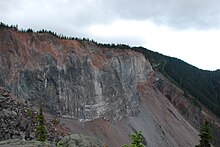 A large rocky cliff rising above rubble at its base