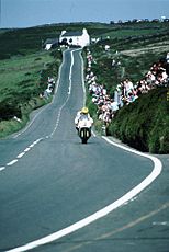 Joey Dunlop bij Creg-ny-Baa met op de achtergrond Kate's Cottage