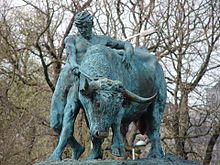 Statue de bronze montrant un puissant taureau maintenu par un homme nu