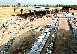 Vestiges au sol avec une colonne en arrière-plan et une toiture moderne de protection.