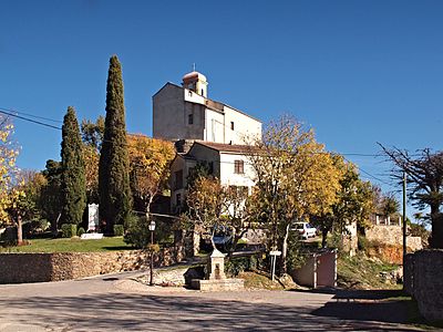 Place Fuata - avec de gauche à droite : le monument aux morts, l'église, la fontaine et l'abri-bus.