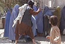 A Taliban religious policeman beating a woman because she removed her burqa in public.