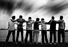 Men standing side by side, arms linked, looking at the sky