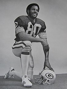 Black and white photo of Lofton kneeling in his uniform