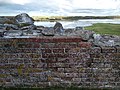 Kalø slotsruins mur. I baggrunden ses tangen, der forbinder Kalø med fastlandet.