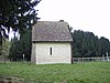 A small structure with a white painted wall and a tiled roof