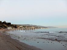 A long shot of a beach with houses in the distance.