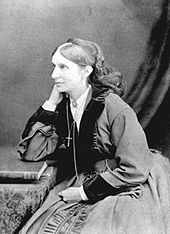 Das Schwarz-Weiß-Foto zeigt Josephine Butler mit fast fünfzig Jahren. Sie ist im Halbprofil zu sehen, da sie links aus dem Bild schaut. Sie sitzt leicht zum Tisch rechts neben ihr gebeugt und hat den rechten Ellbogen auf den Tisch gestützt, ihre rechte Hand fasst an ihre rechte, nicht sichtbare Gesichtshälfte. Der andere Arm liegt in ihrem Schoß. Ihre Haare sind gescheitelt und hinten zusammengefasst, vermutlich in einem Dutt. Auf dem hinteren Oberkopf ist eine flache Kopfbedeckung befestigt, von dem ein Tuch oder Schleier bis zur Schulter herabfällt. Sie trägt ein Kleid mit bauschigem Rock und bauschigen Ärmeln. Der Kragen sowie die Ärmelenden sind mit Fell besetzt. Unter dem Kleid trägt sie eine helle Bluse, die unter dem V-Ausschnitt des Kleides und an den Ärmeln sichtbar ist. Der Blusenkragen ist mit einer Brosche geschlossen. Sie hat eine Kette mit einem Kreuz um den Hals, das Kreuz hängt auf Brusthöhe. Dabneben hängt noch ein Kettenstrang bis in den Schoß. Auf dem Tisch liegt ein Buch, das vor ihrem aufgestützten Ellbogen zu sehen ist. Der Hintergrund ist eine einfarbige Wand, vor dem rechts ein Tuch hereinragt.