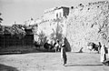 Locals stroll past Qatif Castle, highlighting its towering walls and ramparts.