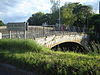 Arched bridge with metal railing. Sign showing River Parrett, Burrow Bridge.