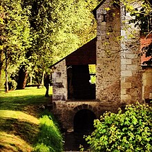 Photographie en couleurs d'un appentis dissimulant la roue à aubes d'un moulin.