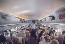 Intérieur d'un avion de ligne, montrant des rangées de six sièges, séparées en leur milieu par un couloir central.