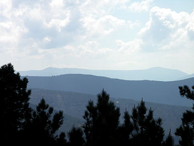 The more distant mountains are, the lighter and more blue they are. This is called atmospheric perspective or aerial perspective.