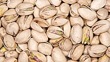 A tan, roasted pistacho shell with the seed visible through a gap in the shell