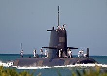 A submarine with people wearing white uniforms standing on the outer hull