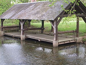 Photographie en couleurs d'un bâtiment en bois au bord d'un plan d'eau.