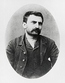 Portrait photograph of Errico Malatesta, wearing a suit and a moustache, with short hair and unkempt stubble