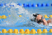 Kristel Köbrich im Wasser, zu sehen sind ihr Kopf die schwarze Bademütze und ihre Schwimmbrille sowie die gelben Bahnmarkierungen.