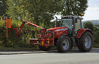 A tractor-mounted hedge trimmer ("hedge cutter")