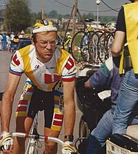 Photographie d'un homme sur un vélo, vêtu d'un haut jaune et blanc, d'un cuissard jaune et noir et porteur d'un casque et de lunettes