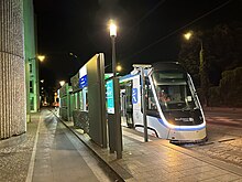 Face avant de la rame TW 20 no 4 à la station Cimetière de Saint-Denis en essais nocturnes dans une livrée blanche avec le logo IDFM en bleu sur le flanc. Le nez de la rame est parcouru par un bandeau lumineux blanc