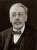 head and shoulders shot of an elderly man with full head of hair, moustache and pince-nez