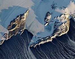 Satellite image with ocean at the bottom flanked by two rocky ridges and ice shelf at the top