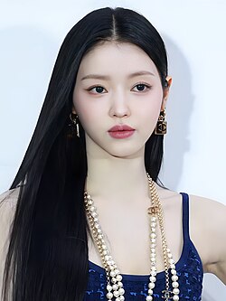 Yooa in a dark blue dress with multiple strands of pearl necklaces around her neck