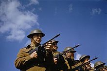 Soldats en uniforme en une rangée pointant une mitrailleuse et portant des casques