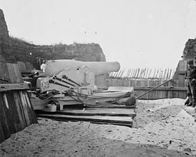 A nine-inch (229 mm) Union navy Dahlgren gun set up on land for siege work as they were at battery ten at Port Hudson. The gun is whitewashed so it can be more easily worked at night. The projections at the breech are for the navy double vent percussion firing system. The crewman at the far right is wearing the Union navy uniform.