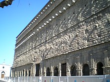 Mur extérieur soutenu par des arches et portant des pièces saillantes dans le haut.