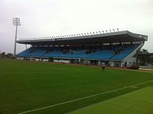 Photographie en couleur d'une partie d'un stade de football et d'une tribune en arrière-plan.