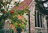 Part of a stone and brick chapel with a red tiled roof seen from an angle