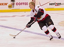 man in white hockey equipment on ice skating with puck