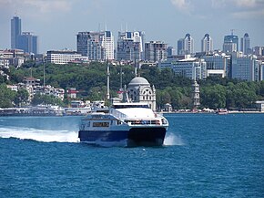 Судно Seabus в заливе Босфор, на фоне небоскребов бизнес-района Левент на заднем плане. Небоскрёб «Сапфир» — первая башня слева.