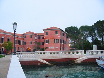 Photographie couleur d'un quai avec un double escalier descendant dans l'eau. En arrière-plan, un bâtiment de deux étages à la façade rose.