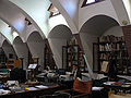 Intérieur des anciennes écuries avec aperçu des fenêtres trapézoïdales et des arcs paraboliques.