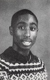 An 18-year old Tupac Shakur smiling for a yearbook photo, black and white