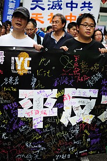 Chinese marchers holding up a black signed banner '平反六四' sign in the background reads "Heaven destroy the Communist party"