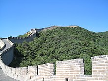 The Great Wall of China, surrounded by trees, against a blue sky