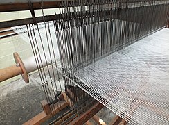 Wire healds on wire staves. A few extra healds have not had warp threads drawn in through them.