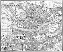 Kupferstich eines Stadtplans mit deutschen Beschriftungen. Ein Fluss namens Düna fließt durch sie hindurch. Alle Straßen, bebauten Flächen und Felder sind eingezeichnet. In der rechten oberen Legende steht der Maßstab 1 zu 70000. In der linken unteren Ecke ist von der Altstadt ein Ausschnitt mit den wichtigsten Bauten und ihrer Legende.