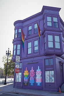 Mural of three plastic containers in the shape of a bear painted in pride flag colors outside of the purple SFLGBT Community Center in October 2020