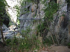 Bas de falaise avec passerelle fixée à la falaise.